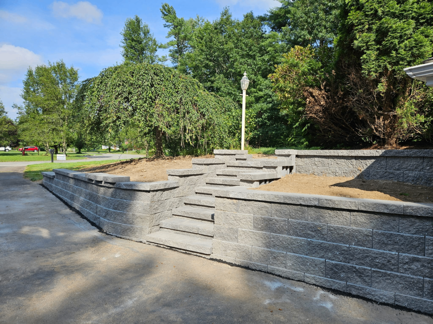 Tiered retaining wall and stone steps built beside a driveway